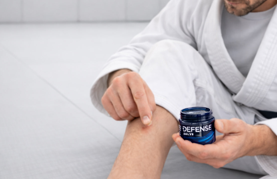 Jiu-jitsu athlete applying Defense Soap salve to a minor mat burn after training.